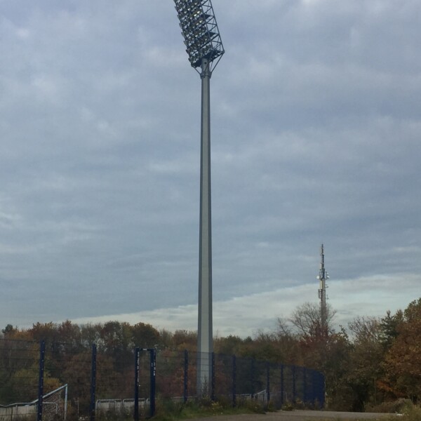 Ein Flutlichtmast des Parkstadions steht vor einem bewölkten Himmel.