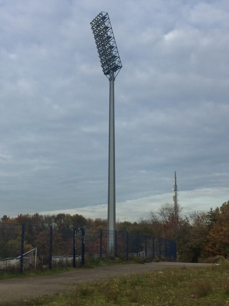Ein Flutlichtmast des Parkstadions steht vor einem bewölkten Himmel.